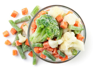 Wall Mural - Frozen vegetables in a plate and sprinkled on a white. Top view.