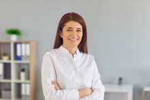 Happy Positive Woman In Lab Coat Standing Arms Folded Looking At Camera. Portrait Of Reliable Medical Professional At Work. Profile Picture Of Young Doctor, Smiling Hospital Staff Or Online Consultant