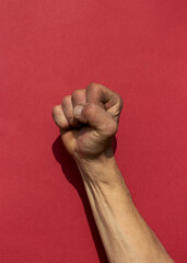 Swarthy rough mans hand with clenched fist on red background. Cesar Chavez Day concept.