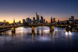 Fototapeta  - The skyline of Frankfurt at sunset, seen from a bridge at the river Main at a cold day in winter.