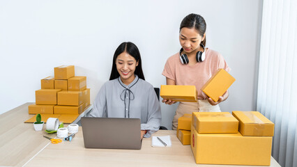 Two young business woman entrepreneur are talking and holding parcel box