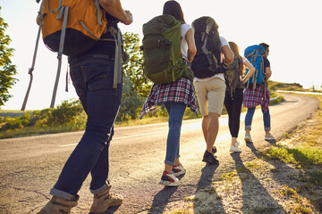Wall Mural - group of people with rucksacks walking along countryside road. tourists hiking in wilderness on summ
