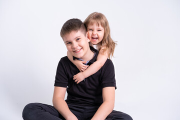 handsome older brother teenager hugging his cute little sister on white background