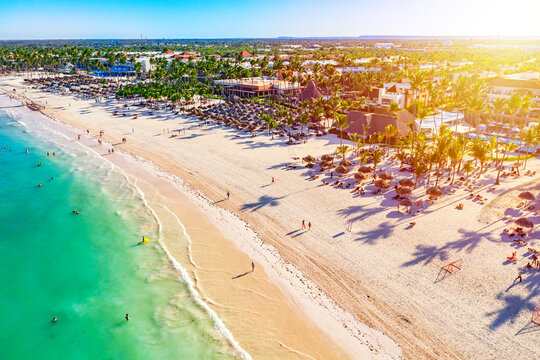 Wall Mural -  - Beach vacation and travel background. Aerial drone view of beautiful atlantic tropical beach with straw umbrellas, palms and boats. Bavaro beach, Punta Cana, Dominican Republic.