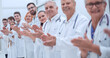 © ASDF - smiling female doctor standing in front of her applauding colleagues.
