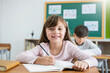 © paulaphoto - Portrait of smile little caucasian pupil writing at desk in classroom at the elementary school. Student girl doing test in primary school. Education knowledge children writing notes in classroom.