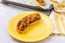 Stuffed Delicata Squash On A Yellow Plate With Another Baked Delicata Squash On Parchment-Lined Baking Sheet In Background
