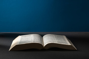 Open bible on a dark background in a light beam.