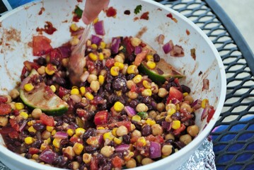 Wall Mural - hand stirring fresh black bean and corn salad in a large serving bowl