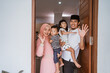 © Odua Images - portrait of muslim family standing in front of their front door house welcoming guest at home during eid mubarak celebration