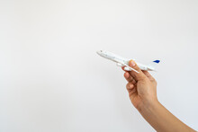 Travel And Destination Concept. Closeup Of Woman Hand Holding Mini Jet Airplane Model On White Background.