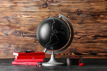 Globe, graduation hat and books on wooden background