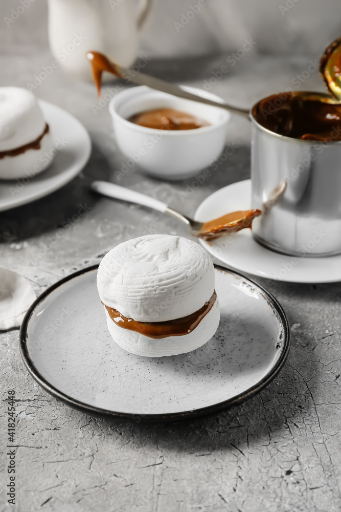 Tasty marshmallows with boiled condensed milk on grunge background