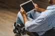 © fotofabrika - Disabled young african american man sitting in wheelchair and using digital tablet