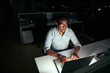 © StratfordProductions - African young business man working at the laptop till late at night in dark office