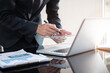 © NINENII - Businessman working at home with tablet and laptop computer and papers on desk.