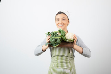 Picture of a smiling attractive woman holding a wooden plate of cauliflowers