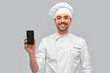cooking, culinary and people concept - happy smiling male chef in toque showing smartphone over grey background