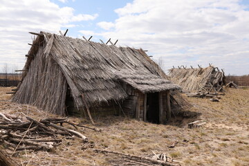 remnants of Ancient houses made from hollow logs with wooden and thatched roofs on the meadow