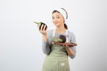Wall Mural - Picture of a nice young woman model in apron holding an eggplant