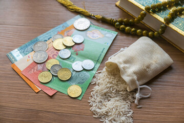 Concept of zakat in Islam religion. Selective focus of money, rice, rosary beads and Quran on wooden background