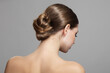 © Alena - Woman with bun hairstyle on gray background. Bare back, shoulders and neck. Back view