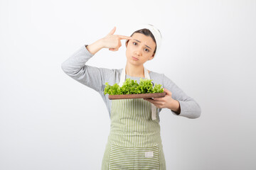 Wall Mural - Portrait of a pretty cute woman holding a wooden board with fresh lettuce