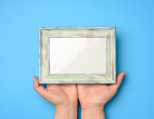 two female hands holding a rectangular blank wooden frame