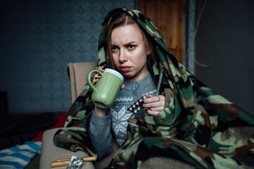 a sick girl drinks hot tea from a mug. treatment of a viral infection at home during an epidemic. take pills and an antipyretic