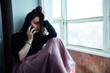 © evgavrilov - a depressed girl sits at the window and talking on the phone