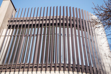 A modern building of glass and steel structures under a blue sky. Parallel lines in architecture. Fragment of a building, office building made of steel and glass.