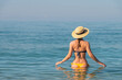 © yanik88 - a slender young woman in a swimsuit and a hat stands waist-deep in the sea water on a sunny day