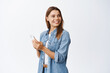 © Cookie Studio - Portrait of happy good-looking woman with blond hair, look right at copy space, holding smartphone, chatting on social media or using mobile application, white background