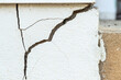 A house white wall with a large crack. Grunge concrete cement white wall with a crack in an industrial building.