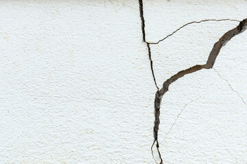 Wall Mural - A house white wall with a large crack. Grunge concrete cement white wall with a crack in an industrial building.