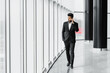 An Indian bearded man walks down the hallway of a modern office, an employee, a businessman, he is in a black suit, a banker