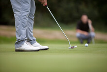 A Golfer Wearing White Shoes Uses A Putter On The Putting Green