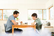 © Connect Images - Boy and father playing chess at living room table