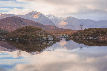 An inspiring mountain landscape reflected on a calm peaceful lake at Rannoch Moor near Glencoe in the Scottish Highlands, Scotland.