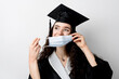 © Rabizo Anatolii - Graduate girl in medical mask at coronavirus covid-19 period. Woman with master degree in black graduation gown and cap. Distance learning online. Study at home. Graduation from college.