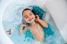Happy, Smiling Girl Taking Bubble Bath In Bathtub