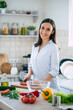 © My Ocean studio - Cute happy young brunette woman in good mood preparing a fresh vegan salad for a healthy life in the kitchen of her home