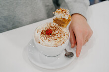 Female Hand Holding A Cup Of Coffee Decorated With Whipped Cream