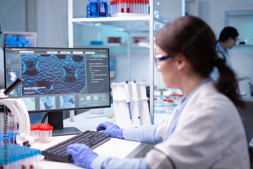 Woman biotechnology scientist working at computer researching in ...
