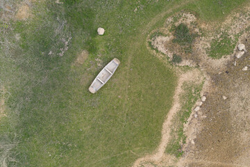 Wall Mural - Aerial top view of wooden boat lying on the lawn on the river bank