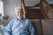 © Daniel - Portrait of old man smiling and looking at the camera sitting on the sofa from home. Closeup male person senior cheerful indoor..