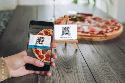 Women\'s hands using the phone to scan the qr code to order pizza. Scan to get discounts or order for pizza.