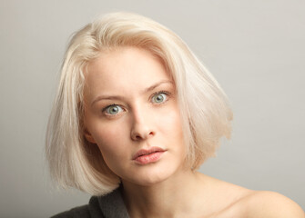 Wall Mural - blond hair woman irritated and anoinng isolated on gray background close-up portrait