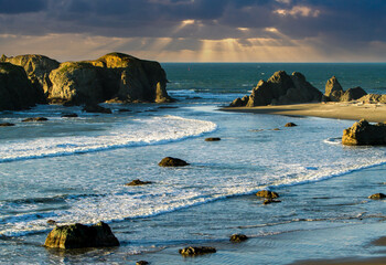 Sun rays behind the Sea Stacks and incoming waves at Bandon beach on the southern Oregon Coast at Bandon.