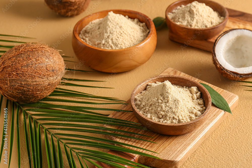 Bowls with coconut flour on color background